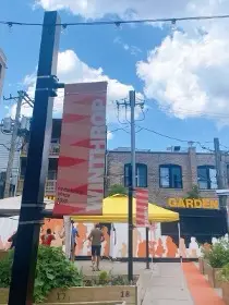 Signs designating the Winthrop Family Historical Garden. In the left corner, community members can be seen participating in an organized dance activity.