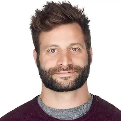 A headshot of a white male with brown spikey hair and full beard. Wearing a maroon sweater and grey t-shirt.