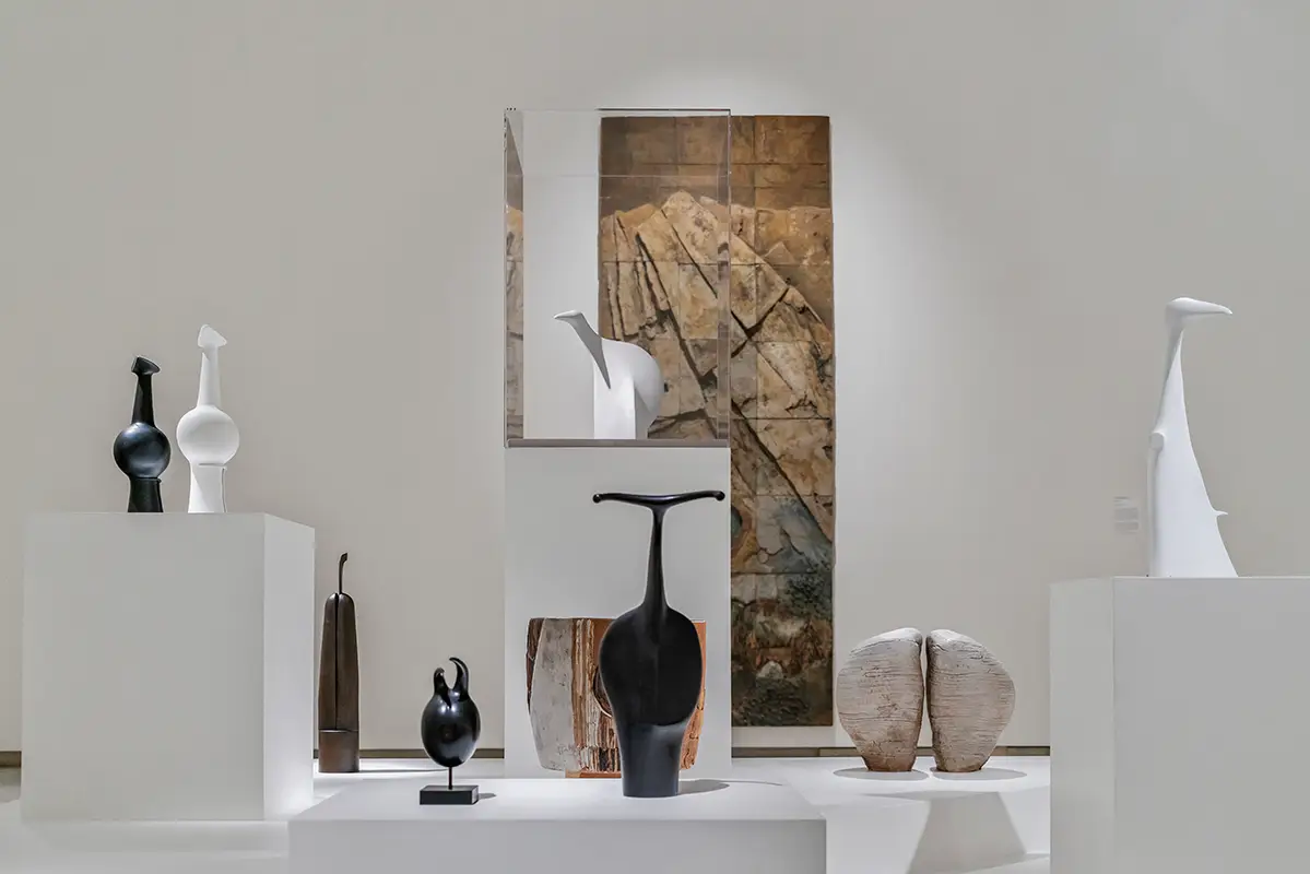 Ceramic sculptures with a variety of organic forms displayed on a series of platforms in a museum