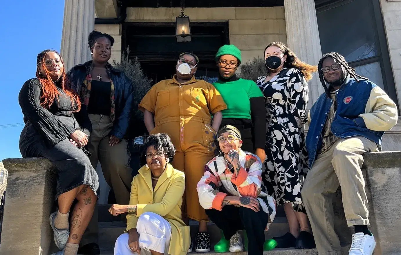 Group photo of members of the Greystone Collective in front of a brick building.