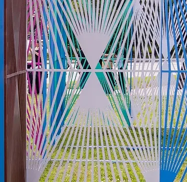 Detail of a pavilion formed from a series of colorful lattice panels installed in a park space.