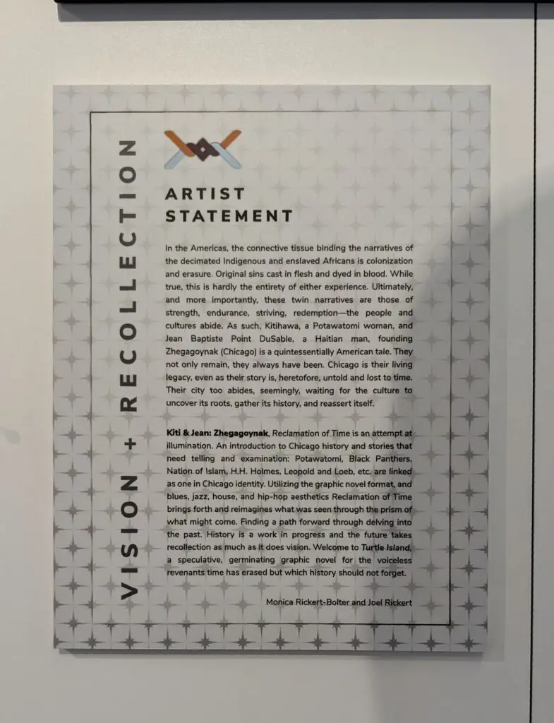 A wall-mounted artist statement by MonicaRickert-Bolter and Joel Bolter titled “VISION + RECOLLECTION” with a starburst pattern background. It features an interwoven orange, blue, and black motif above the title. The text discusses themes of colonization, erasure, strength, and resilience across Indigenous and Black American histories. It references figures like Kitiwaha, Jean Baptiste Point DuSable, and Chicago’s historical complexity. The statement introduces Kiti & Jean: Zhegagoynak, a graphic novel exploring speculative and historical storytelling rooted in Chicago’s cultural identity. Artist Statement: Vision + Recollection. "In the Americas, the connective tissue binding the narratives of the decimated Indigenous and enslaved Africans is colonization and erasure. Original sins cast in flesh and dyed in blood. While true, this is hardly the entirety of either experience. Ultimately, and more importantly, these twin narratives are those of strength, endurance, striving, redemption—the people and cultures abide. As such, Kitiwaha, a Potawatomi woman, and Jean Baptiste Point DuSable, a Haitian man, founding Zhegagoynak (Chicago) is a quintessentially American tale. They not only remain, they always have been. Chicago is their living legacy, even as their story is, heretofore, untold and lost to time. Their city too abides, seemingly, waiting for the culture to uncover its roots, gather its history, and reassert itself. Kiti & Jean: Zhegagoynak, Reclamation of Time is an attempt at illumination. An introduction to Chicago history and stories that need telling and examination: Potawatomi, Black Panthers, Nation of Islam, H.H. Holmes, Leopold and Loeb, etc, are linked as one in Chicago identity. Utilizing the graphic novel format, and blues, jazz, house, and hip-hop aesthetics Reclamation of Time brings forth and reimagines what was seen through the prism of what might come. Finding a path forward through delving into the past. History is a work in progress and the future takes recollection as much as it does vision. Welcome to Turtle Island, a speculative, germinating graphic novel for the voiceless revenants time has erased but which history should not forget. Monica Rickert-Bolter and Joel Rickert"